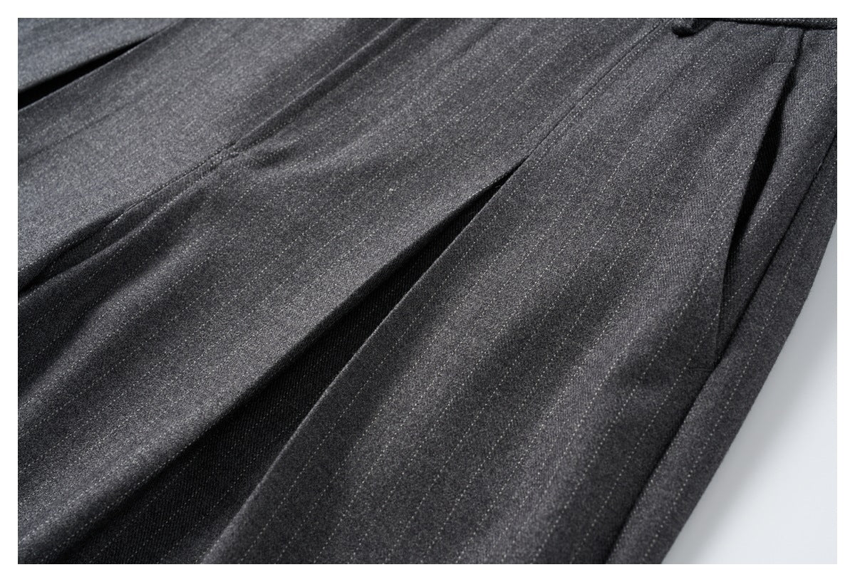 Close-up of charcoal gray trouser legs with front pleats and a side seam.
