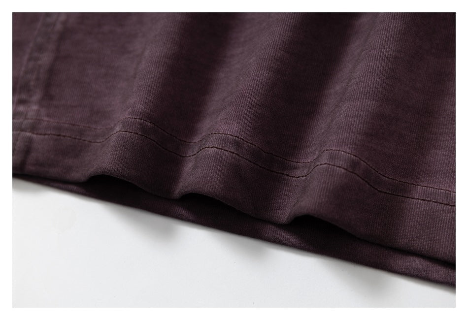 Close-up of the double-stitched hem on a dark plum shirt.