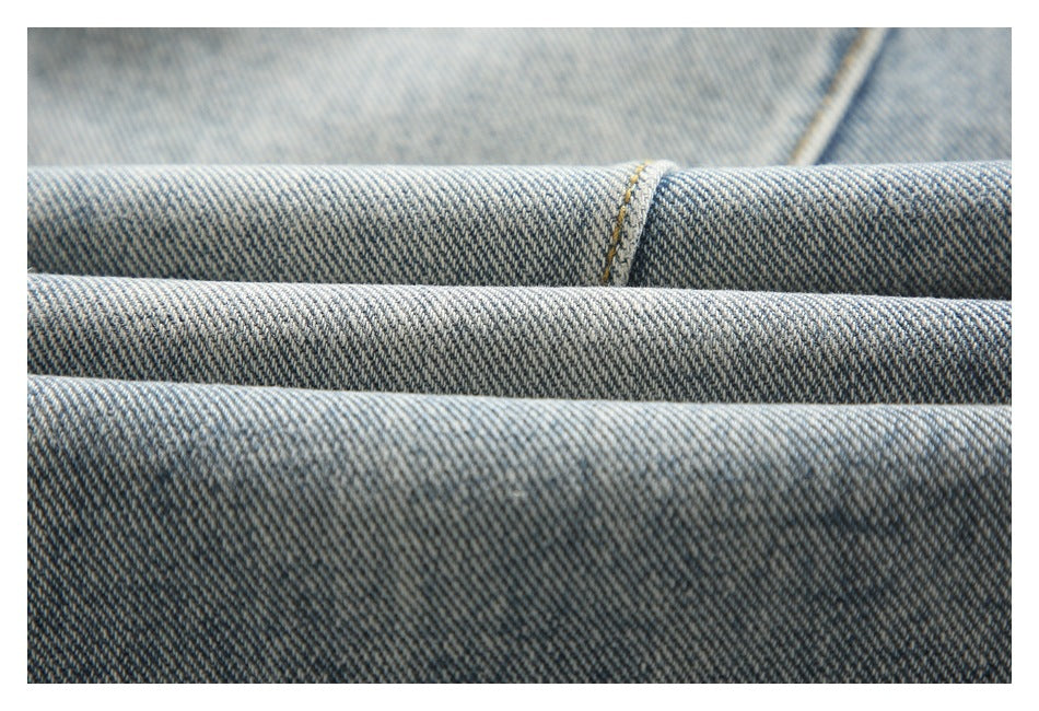 Close-up of layered light blue denim with diagonal twill texture and a stitched seam.