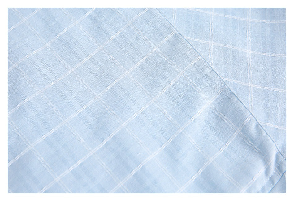 Close-up of pale blue fabric with a raised white grid pattern and a curved folded edge.