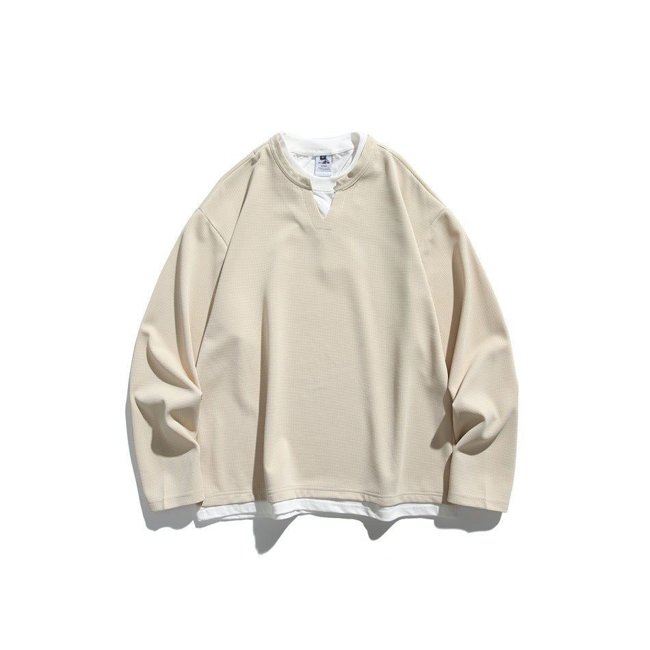 Front view of a cream long-sleeve top with a notched neckline and a white layer visible at the collar and hem.