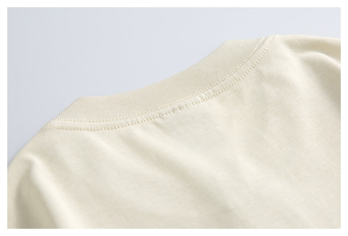 Close-up of the ivory shirt's ribbed crew neckline and shoulder stitching.