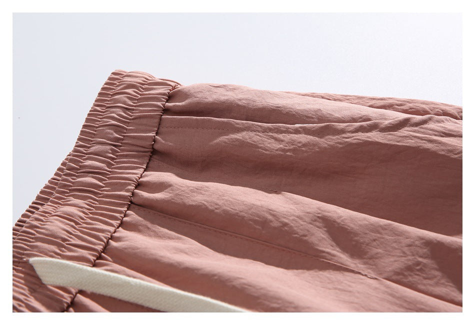 Close-up of the gathered waistband and fabric stitching on the dusty rose pants.