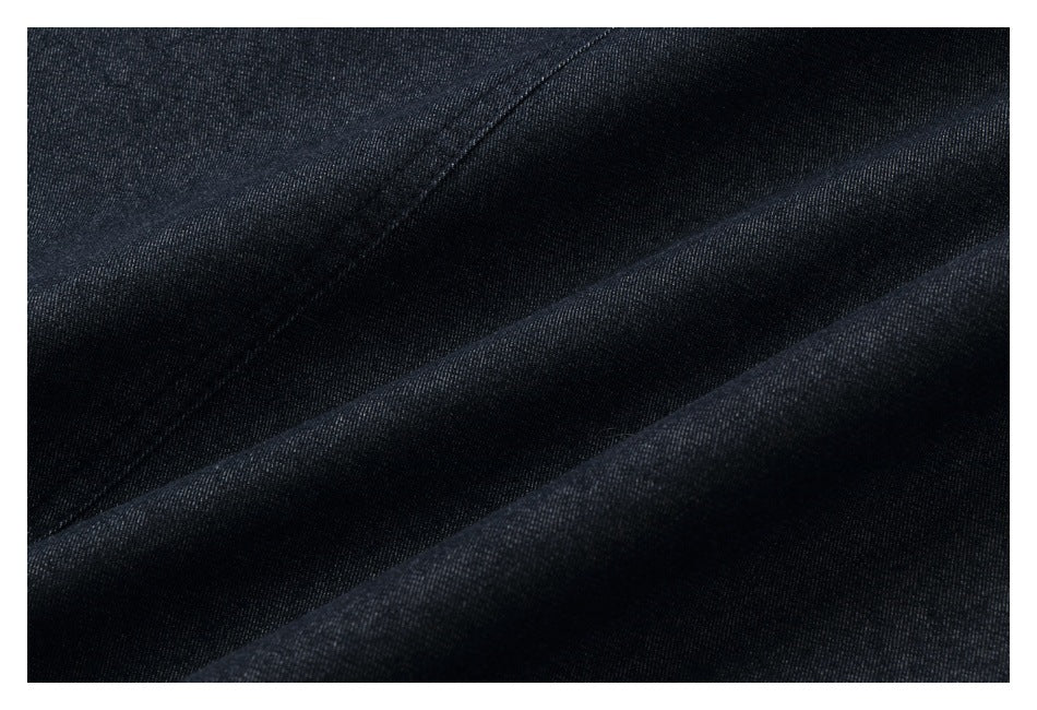 Macro view of dark indigo fabric with a fine diagonal weave and soft folds.