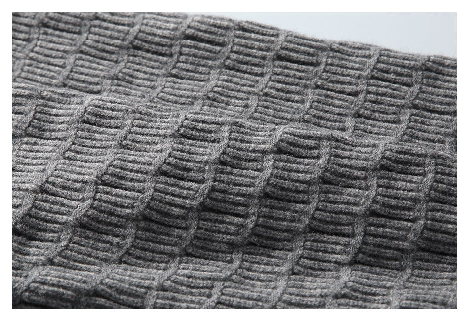 Close-up of a gray knit garment showing a raised, repeating rectangular stitch pattern.