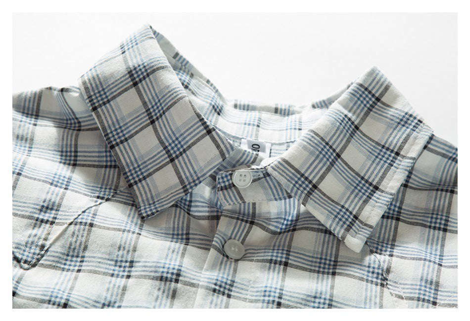 Close-up of the collar and buttoned neckline of a white shirt with blue and charcoal plaid.