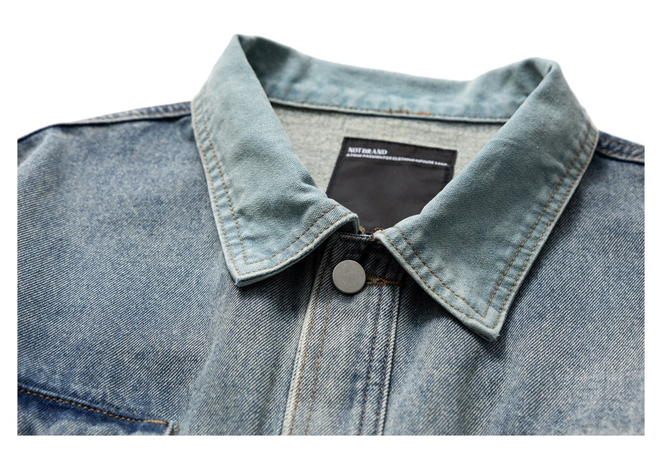 Close-up of a light blue denim jacket collar and upper placket with a metal button and inner label.