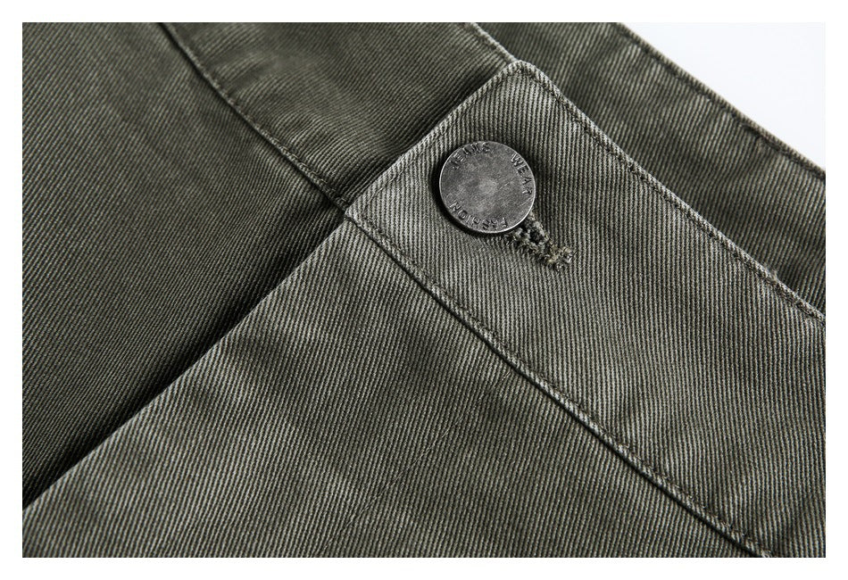 Close-up of olive-gray trouser fabric, waistband stitching, and an engraved metal button.