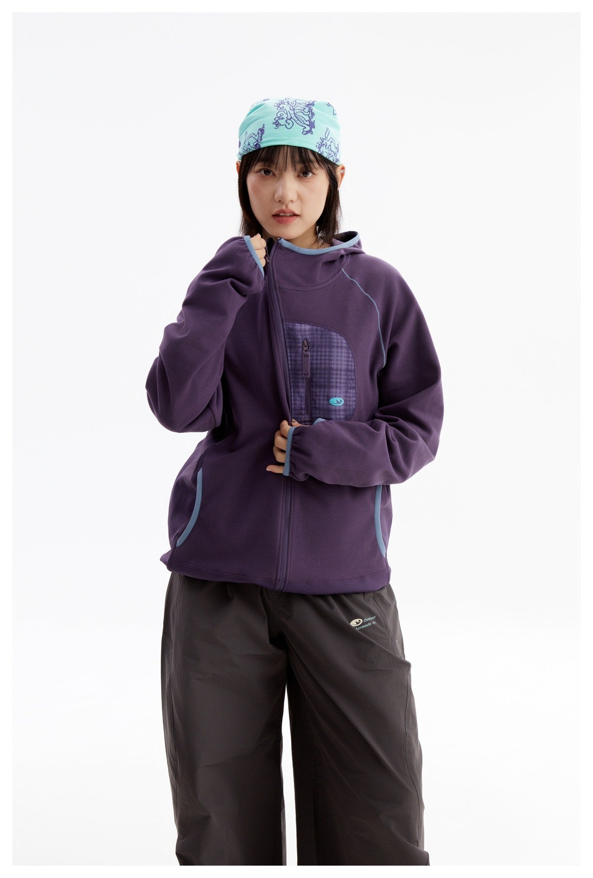 Woman wearing a purple zip-up hooded jacket with blue trim and a checked chest pocket.