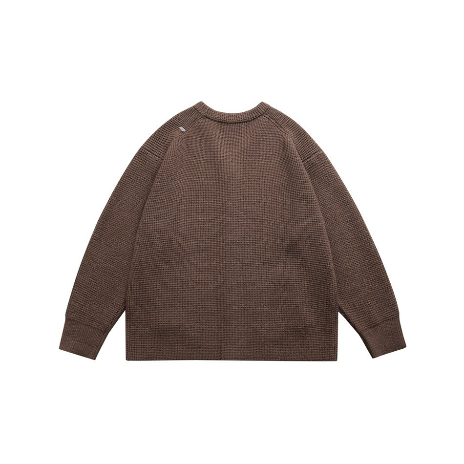 Back view of a brown knit cardigan with raglan sleeves and ribbed cuffs.