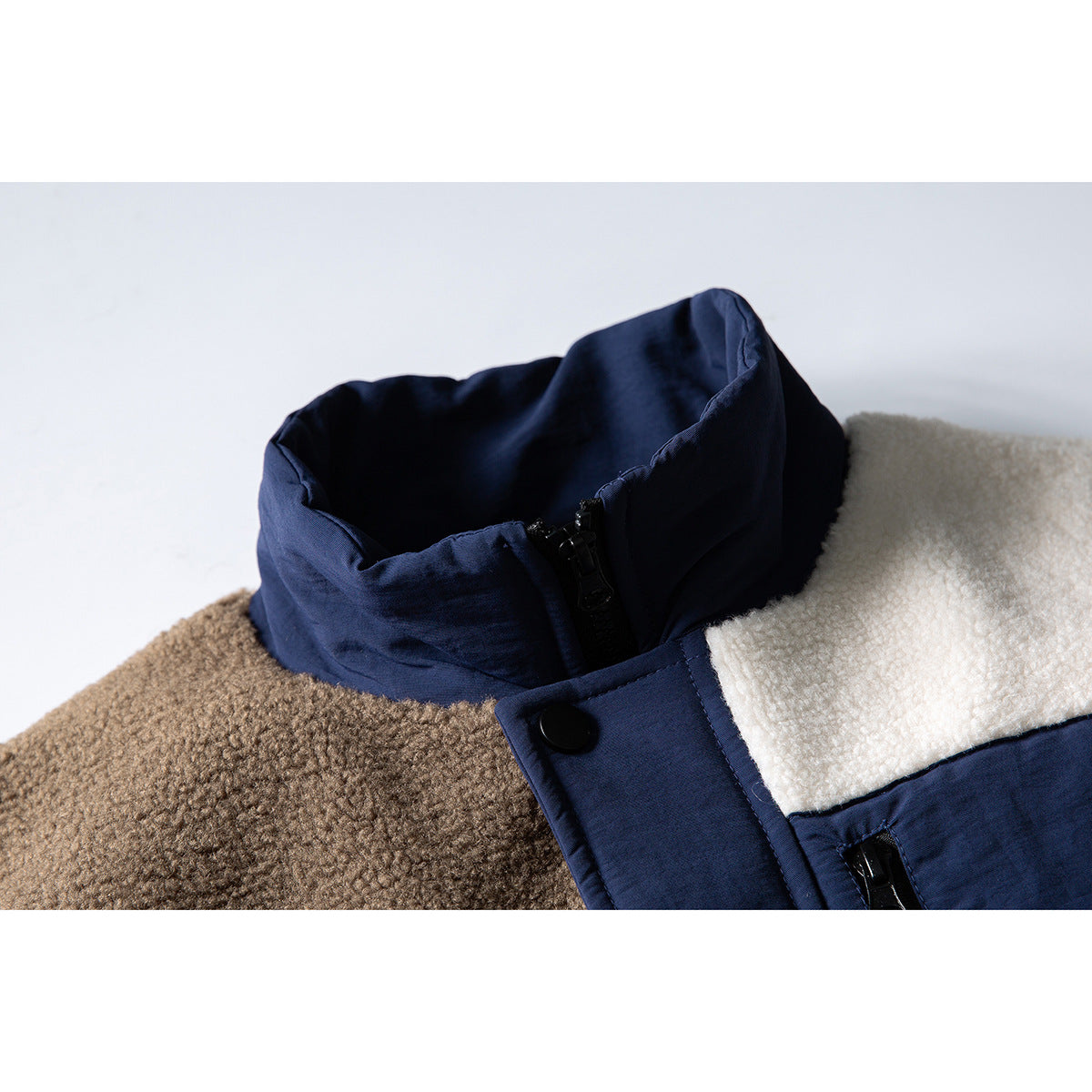Close-up of a navy stand collar and snap placket on a brown-and-cream color-block fleece jacket.