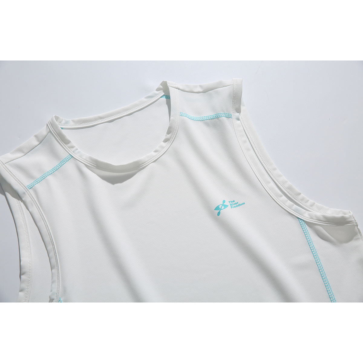 Close-up of a white sleeveless top with turquoise seam accents and a small turquoise chest emblem.