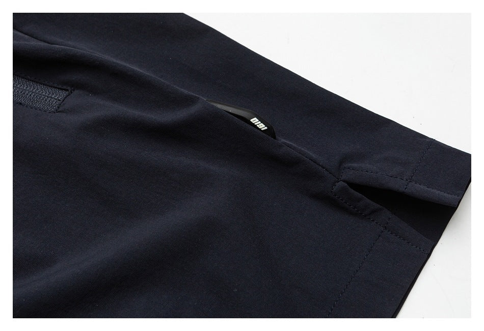 Close-up of a pocket opening and stitched hem on navy pants.