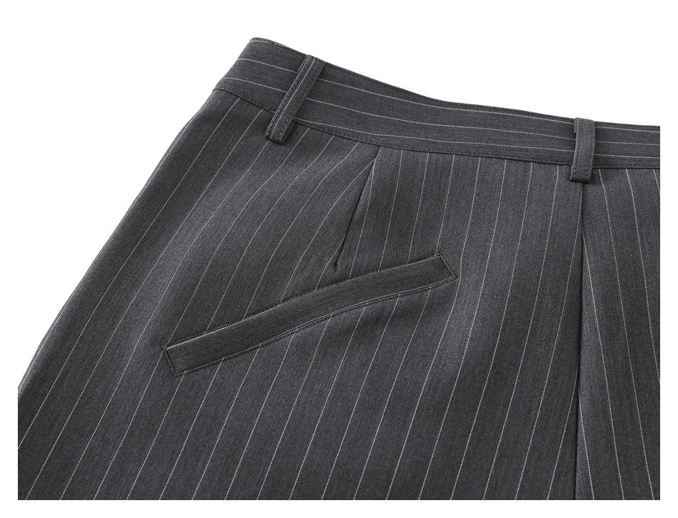 Close-up of the front waistband, pleats, and slanted pocket on charcoal pinstripe trousers.