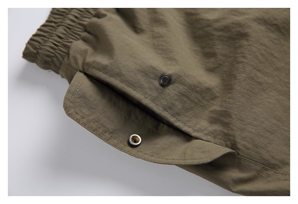 Close-up of a snap-button closure on olive-brown pants.