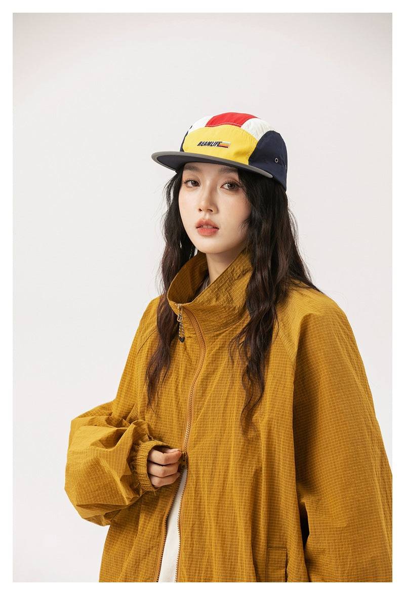 Close view of a model wearing a mustard-gold grid-textured zip jacket with a raised collar.