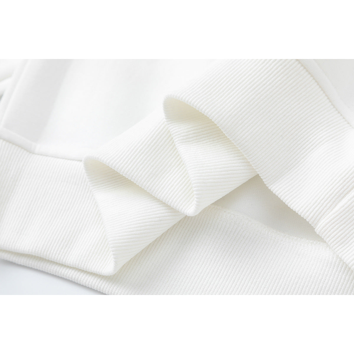Close-up of white sweatshirt fabric and folded ribbed trim.
