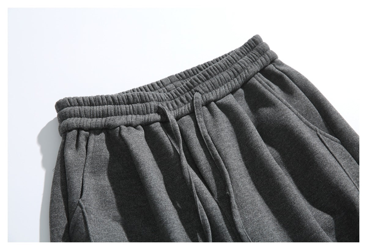 Close-up of dark gray pants with a gathered elastic waistband, drawstring, and angled front pockets.