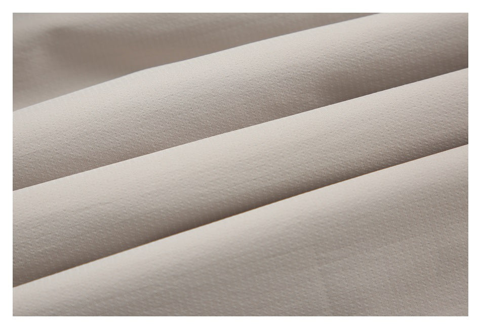 Close-up of the subtle woven texture on light beige fabric arranged in diagonal folds.