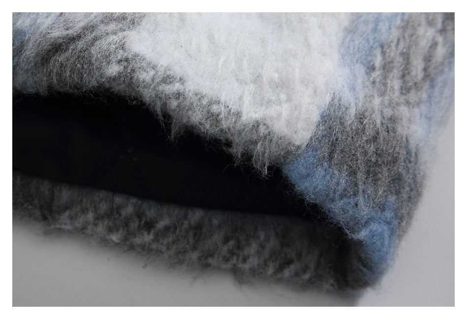 Close-up of the fuzzy blue, gray, and white plaid garment's folded edge and hem.