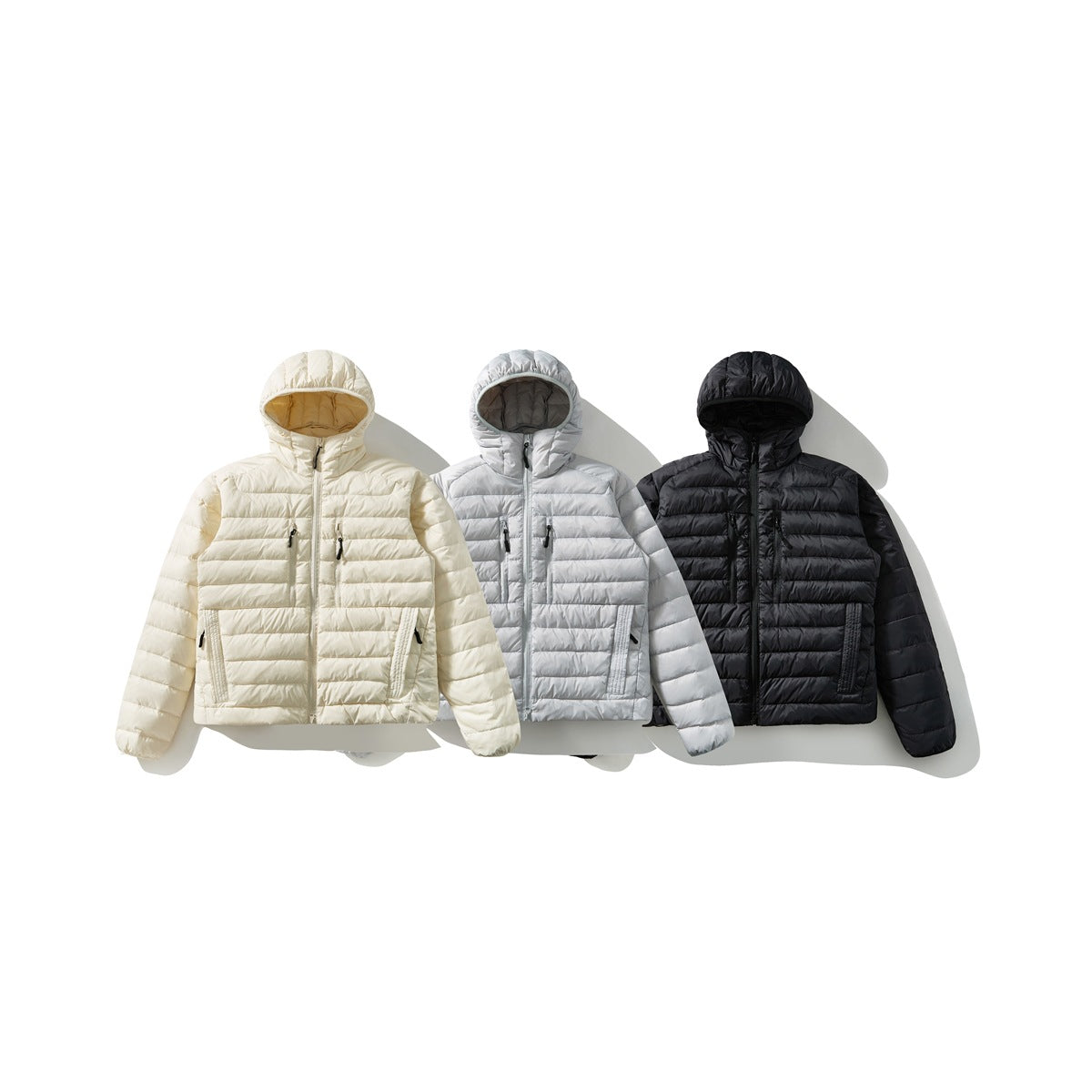 Three hooded quilted jackets shown from the front in cream, light gray, and black.