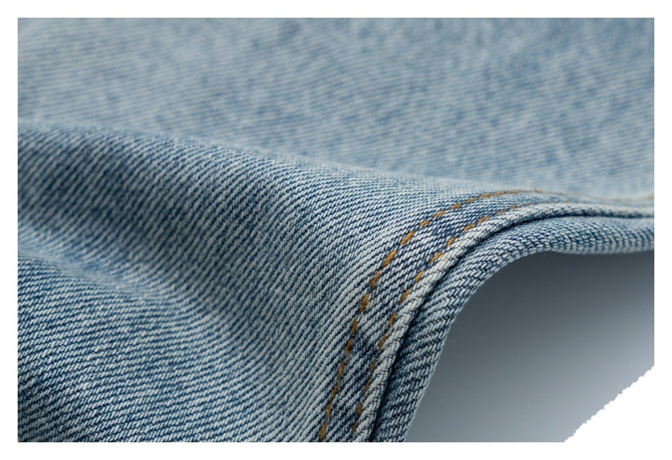 Close-up of a curved, double-stitched seam and folded edge on light blue denim.