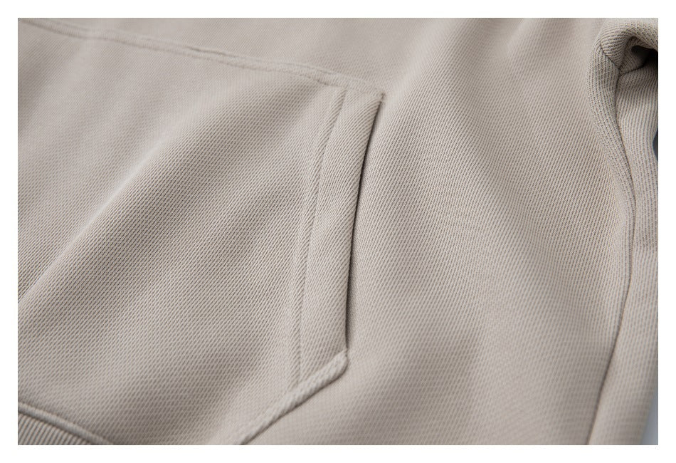 Close-up of the kangaroo pocket opening and side seam on the taupe sweatshirt.