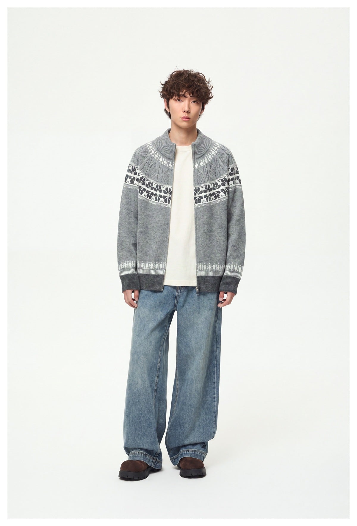 Model wearing open light gray Fair Isle-style zip knit sweater over a cream tee with wide-leg blue jeans