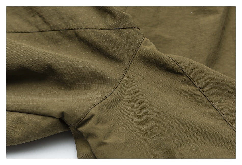Close-up of intersecting seams and construction on olive-khaki pants.