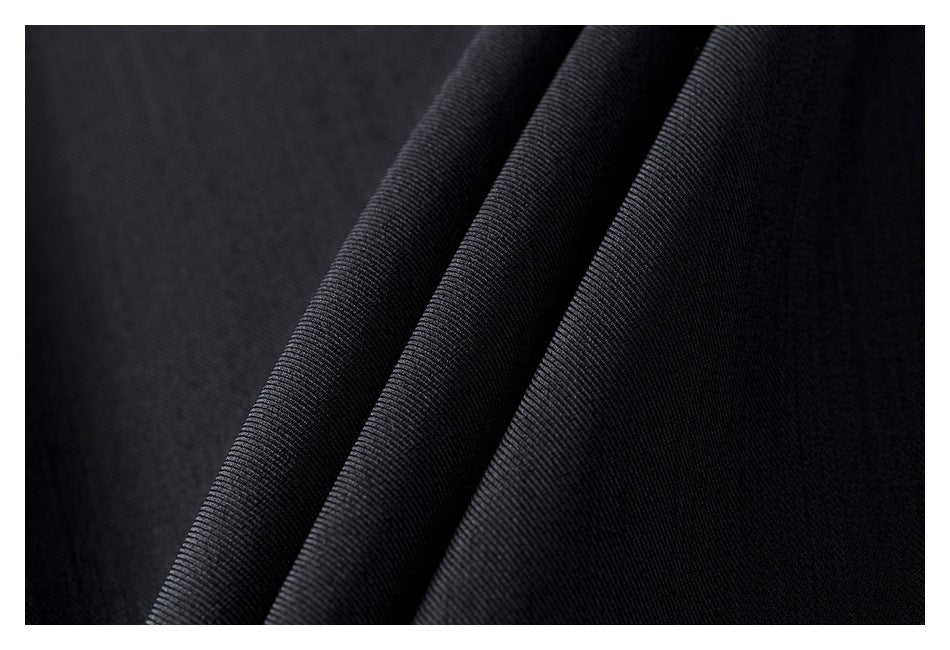 Close-up of dark charcoal fabric draped in folds, showing its fine ribbed texture.