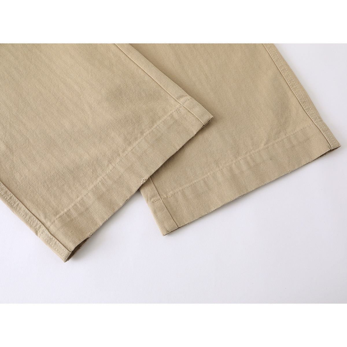 Close-up of tan trouser legs showing the fabric texture and stitched hems.