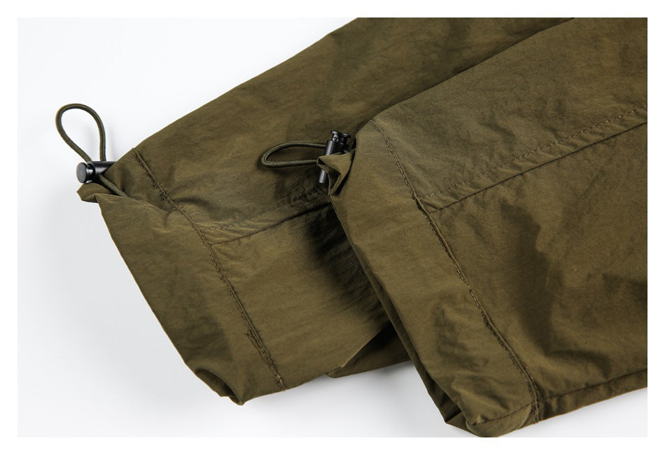 Close-up of an olive garment hem with stitched panels and an adjustable drawcord toggle.