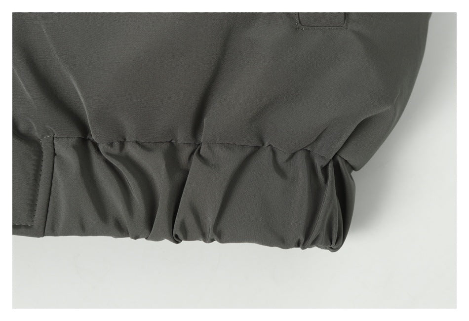 Close-up of the gathered elastic hem and seam on a dark gray jacket.