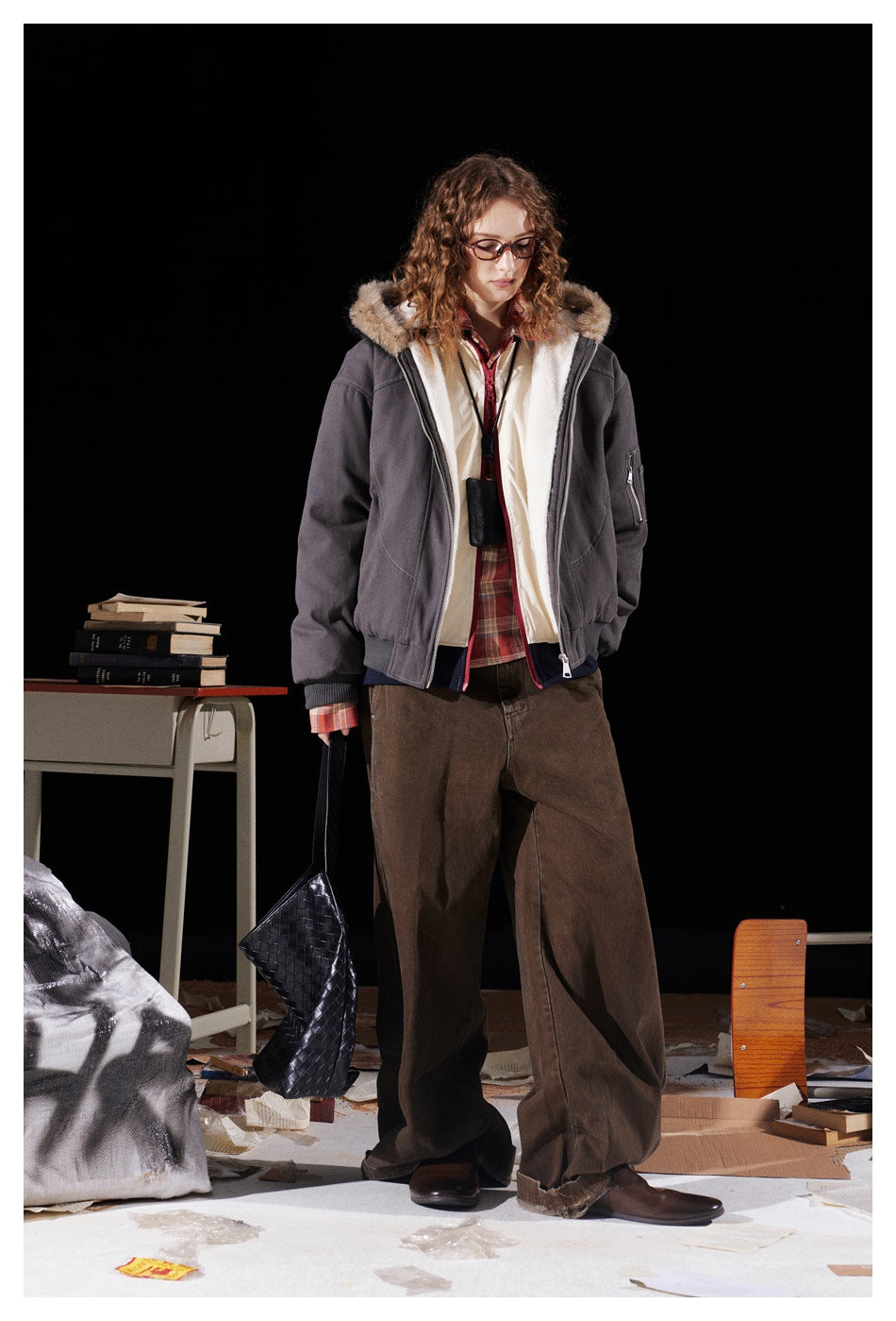 Full-length model wearing an open charcoal hooded jacket with cream lining and a fur-trimmed hood.