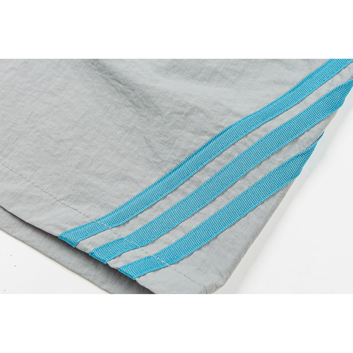 Close-up of gray shorts showing three bright blue woven stripes near the hem.