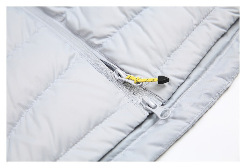 Close-up of the light gray quilted jacket's double zipper, including a yellow cord pull with a black tip.