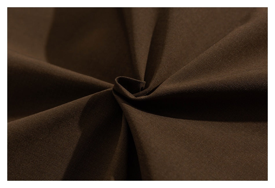 Macro view of brown jacket fabric gathered into soft folds.