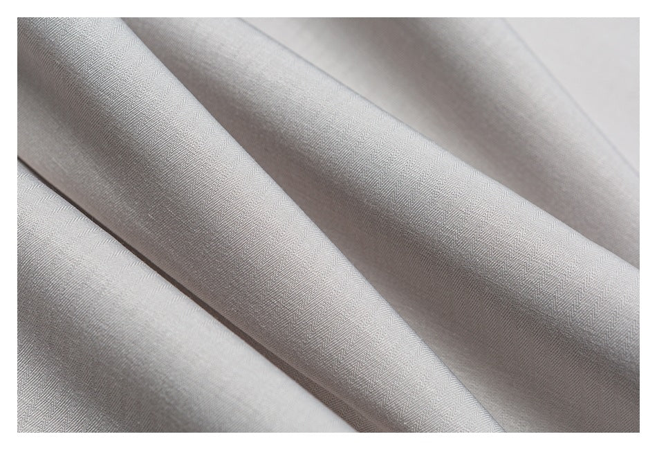 Macro view of light gray fabric with a fine subtle woven texture and soft folds.