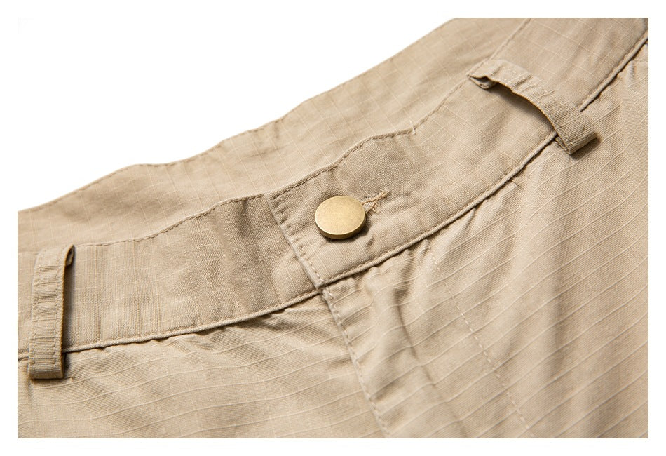 Close-up of a tan garment waistband with a brass-colored button and belt loops.