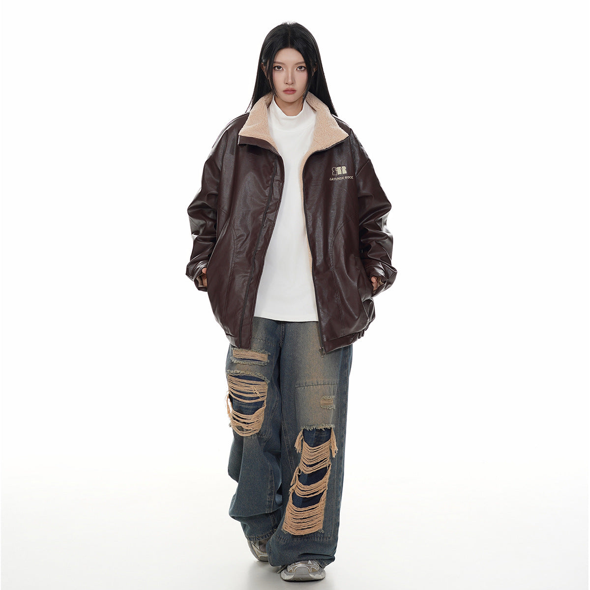 Model wearing an open dark brown jacket with a cream fleece collar over a white top.