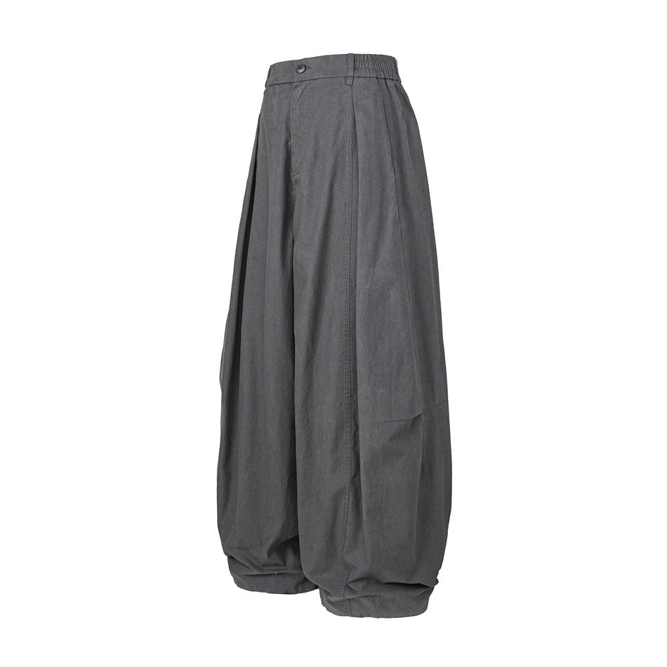 Dark gray wide-leg balloon pants shown from a three-quarter side angle, with elastic waistband and curved leg shape