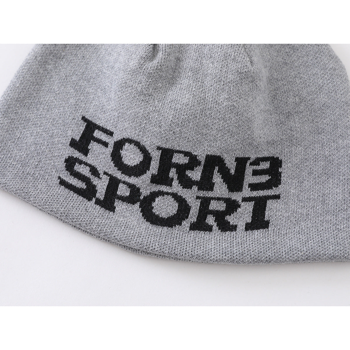 Close-up of a gray knit beanie with bold black “FORNE SPORT” lettering.