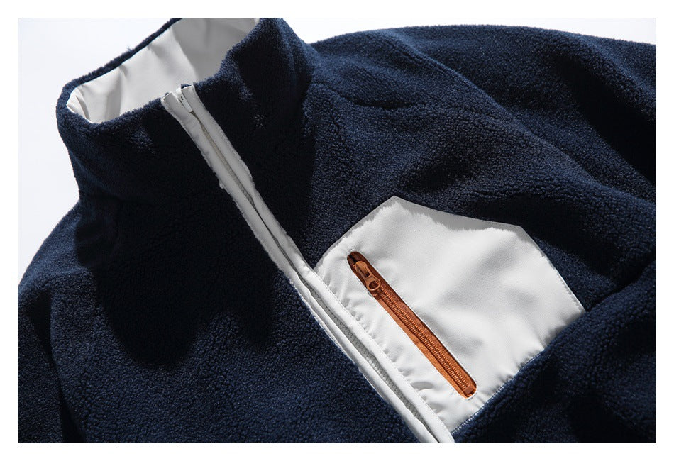 Close-up of a navy fleece jacket collar, white zipper, and contrasting light gray chest pocket with a copper-colored zip.