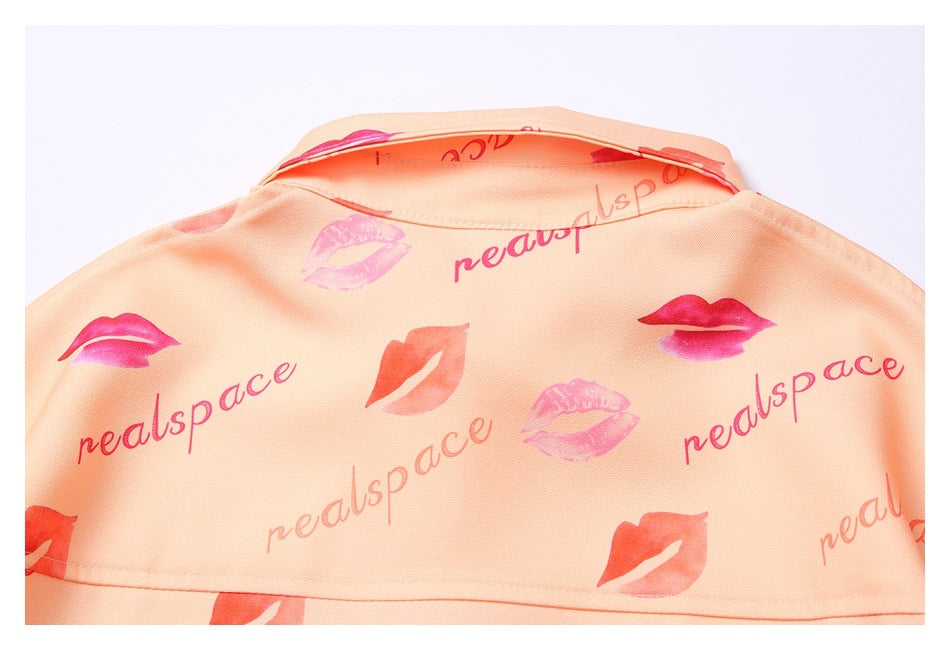 Back view of a peach garment with a collar and repeated pink lip and lettering print.