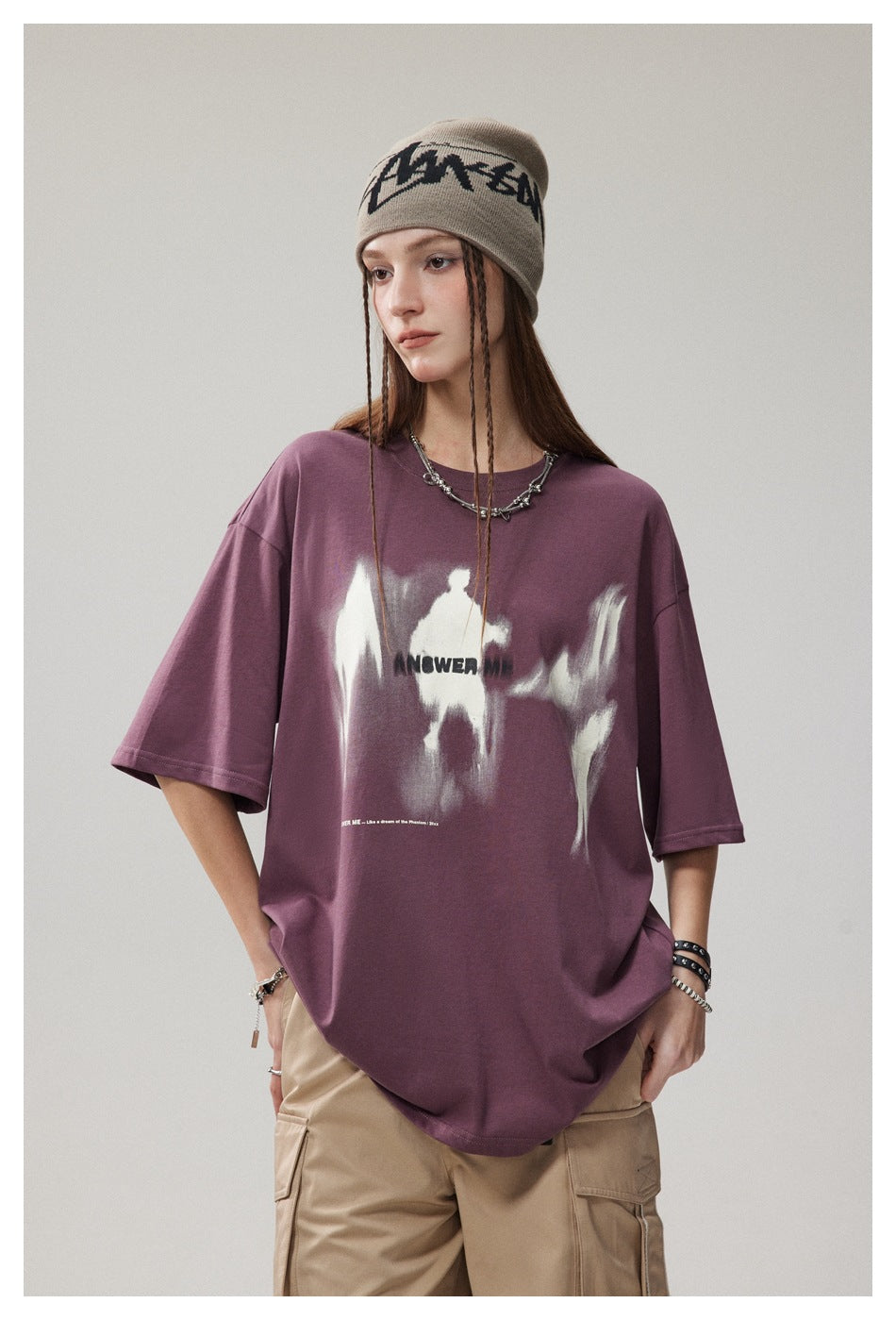Model wearing an oversized plum graphic T-shirt with beige cargo pants and a taupe beanie.
