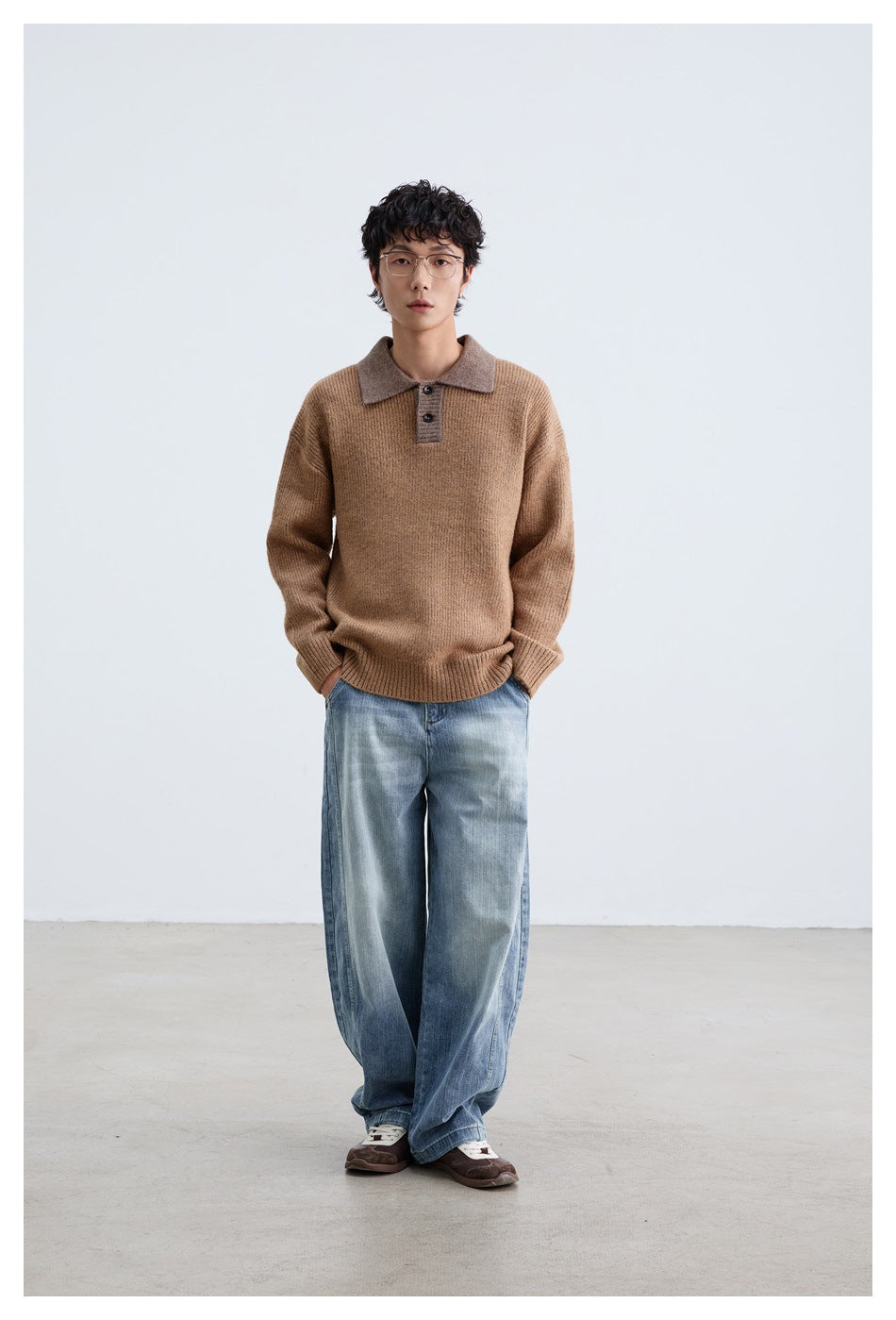 Full-length model wearing a camel-brown knit polo sweater, loose blue jeans, and brown sneakers.