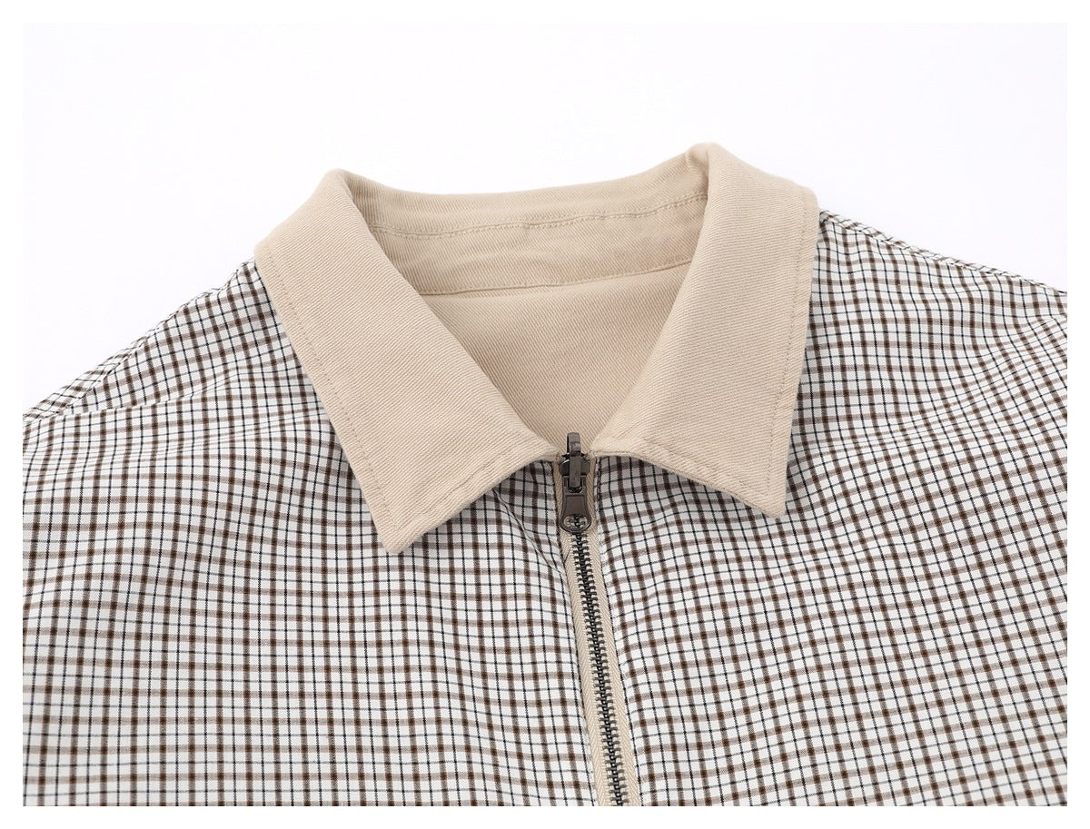 Close-up of the jacket's light beige collar and zipper against white and brown checked fabric.
