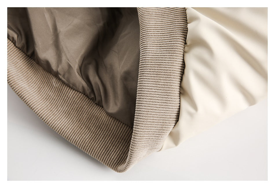 Close-up of the cream jacket's taupe ribbed hem and sleeve trim with the lining visible.