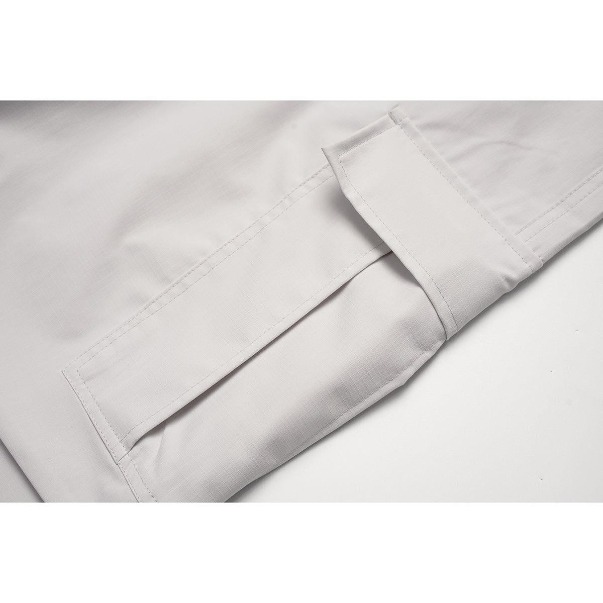 Close-up of a light gray cargo pocket flap and stitched seams.