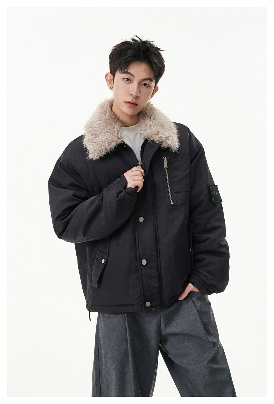 Model wearing a black jacket with a plush beige collar, snap front, zip chest pocket and sleeve patch.